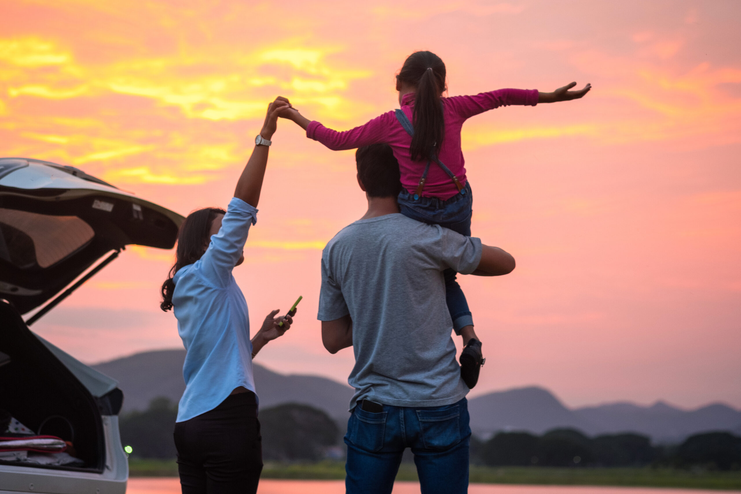 Família alegre ao lado do porta-malas aberto