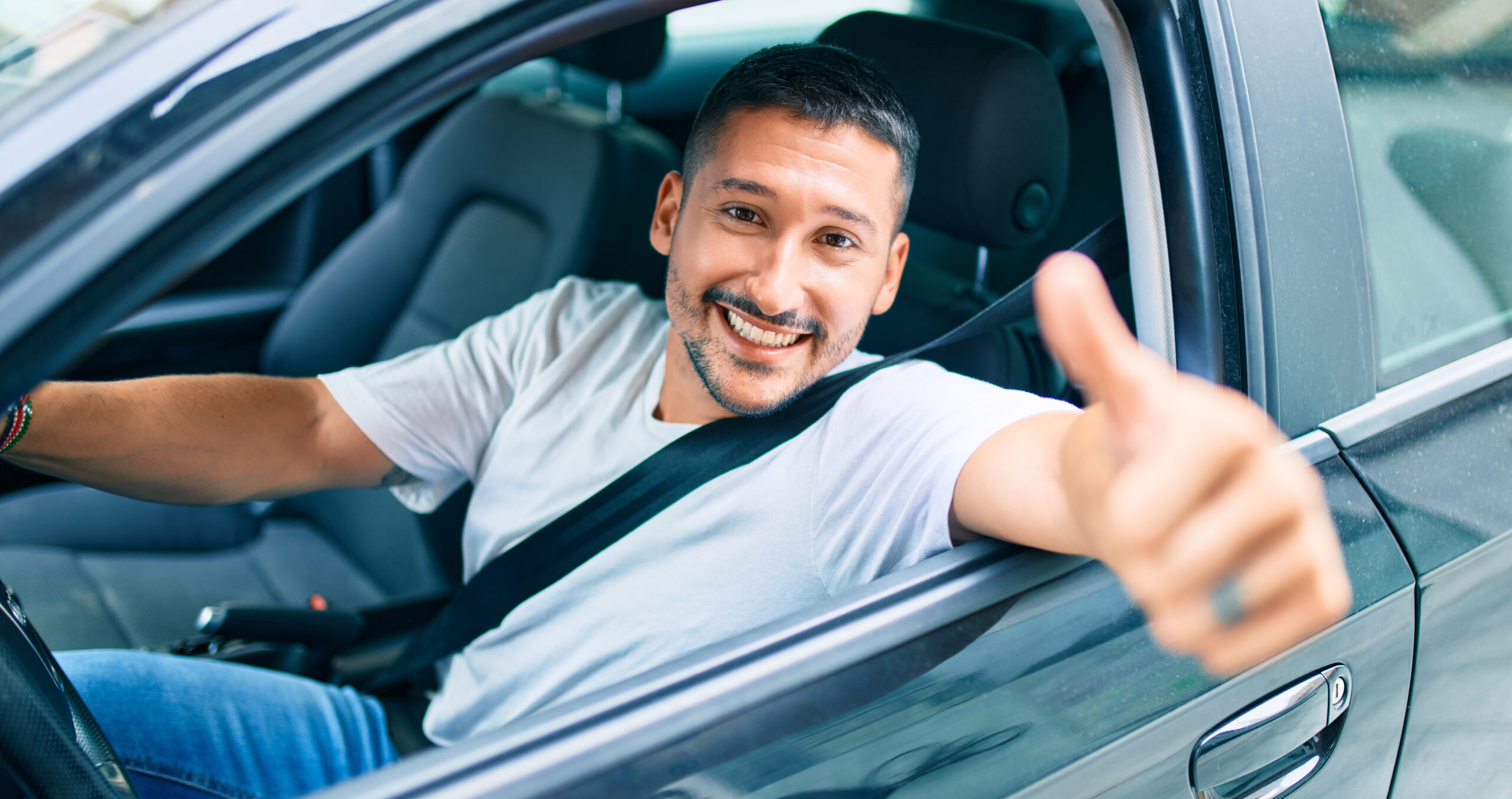 Motorista sorridente dentro do carro com o dedão levantado
